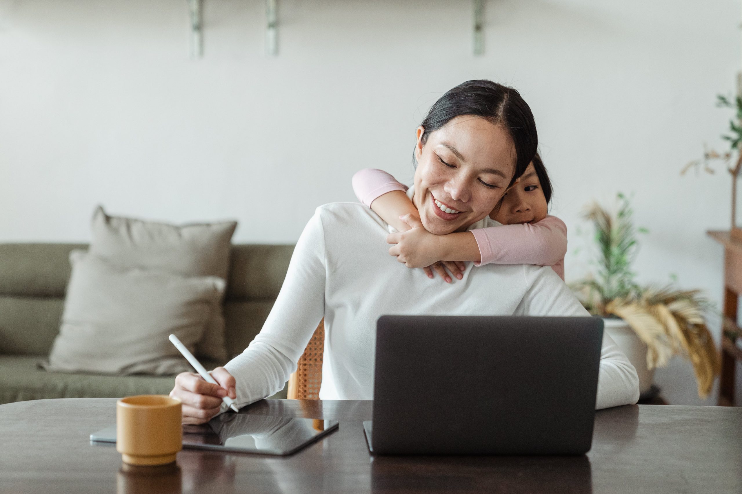 7 Tips for Parent Entrepreneurs - Happy mother working from home and little daughter hugging mom